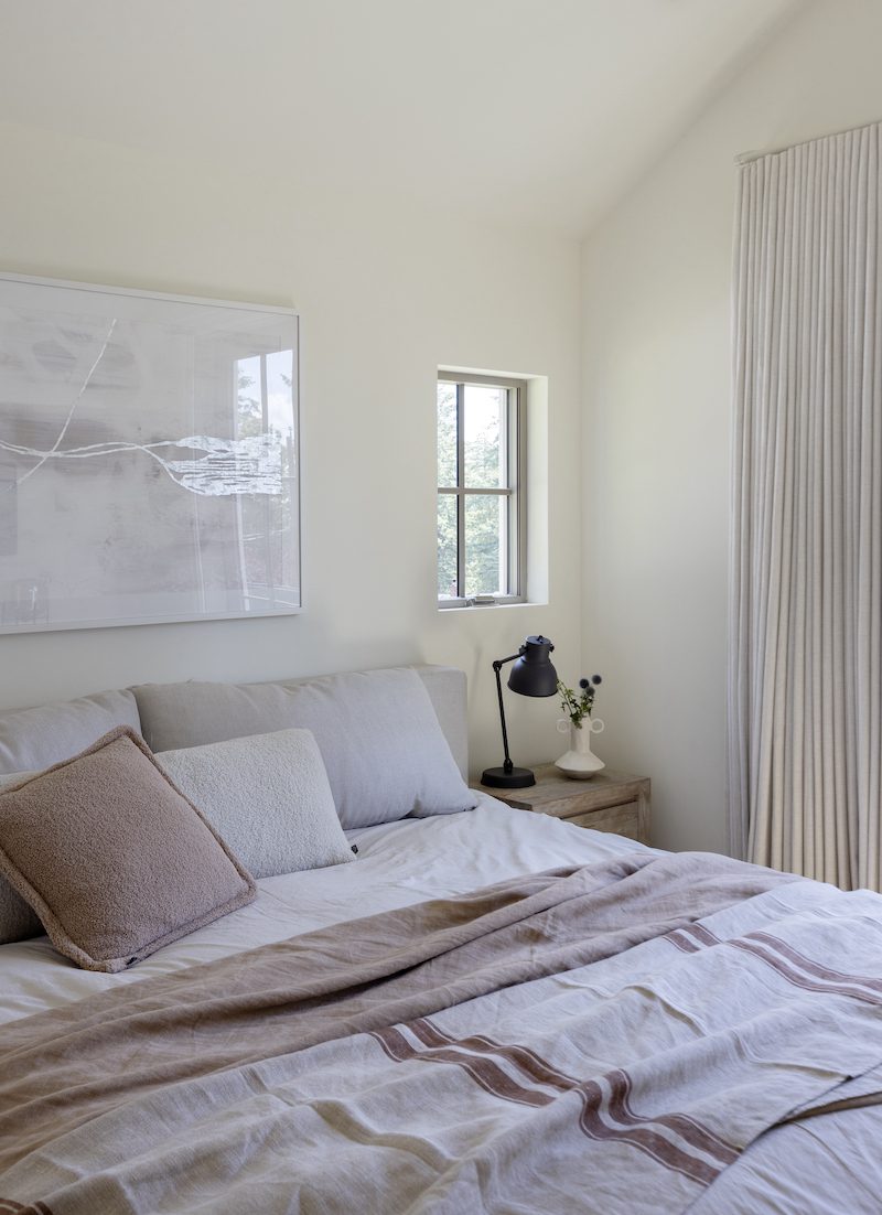 A custom built master bedroom with small farmhouse windows on either side of the bed.