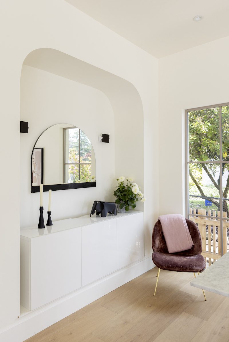 custom built in arched alcove that homes a white laminate hutch and a unique rainbow shaped mirror.