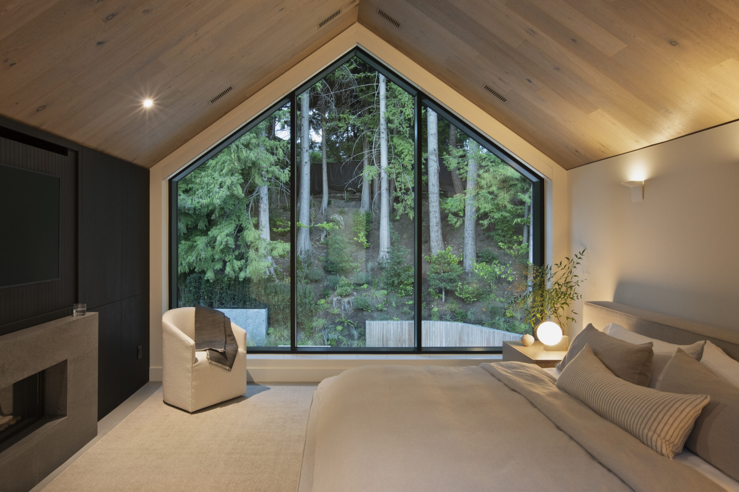 Primary bedroom with large picture window overlooking backyard at Japandia residence